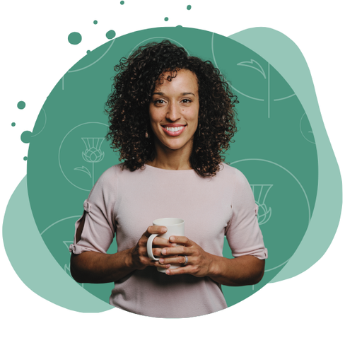 woman smiles holding a cup of coffee with pearl and thistle logos behind her
